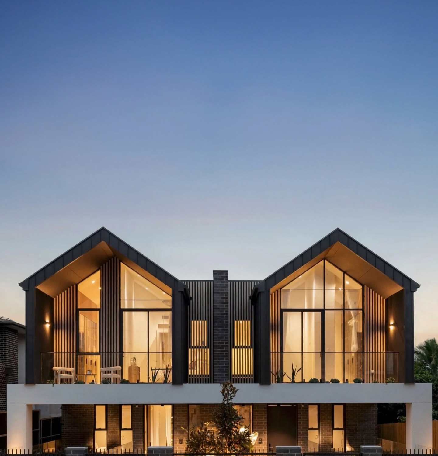 Gabled contemporary duplex at dusk with expansive glazing
